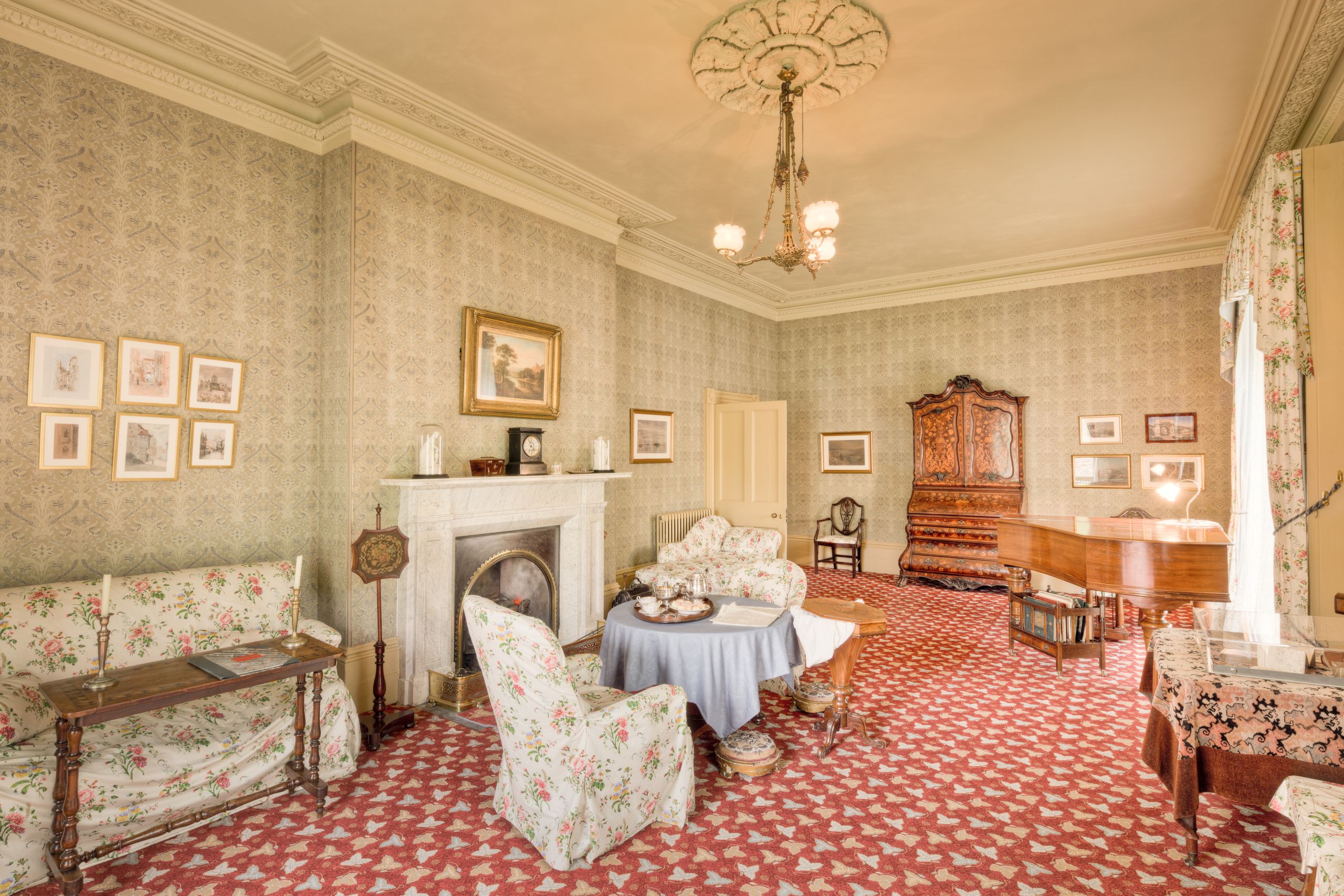 Elegantly furnished drawing room with vintage decor in England, featuring a fireplace and classic furniture.